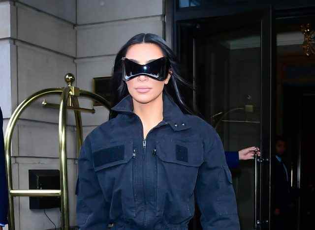 Kim Kardashian trägt eine schwarze Sonnenbrille und eine Jacke vor dem Hotel