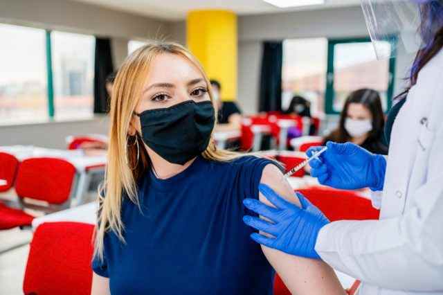 Krankenschwester gibt Schülern während der Coronavirus-Pandemie eine Impfung in der Schule