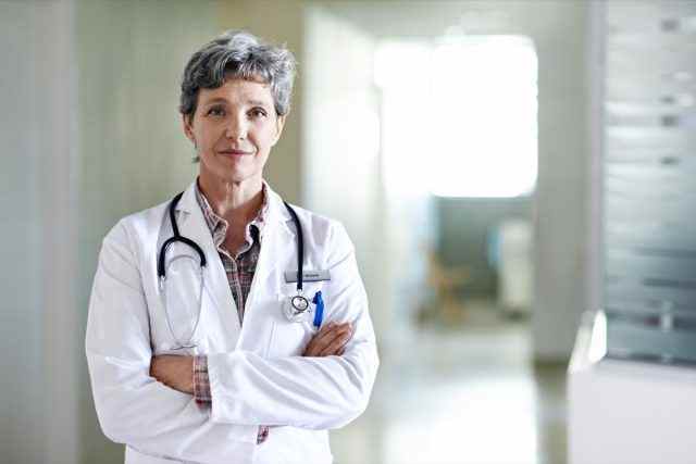 Porträt einer reifen Ärztin, die in einem Krankenhaus steht.