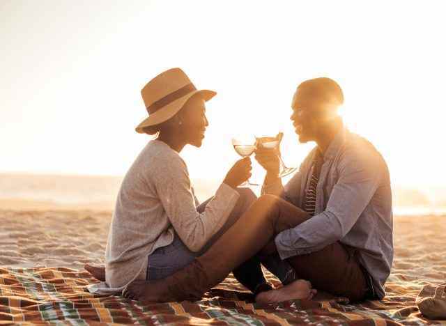 Glückliches Paar stößt Weingläser am Strand an