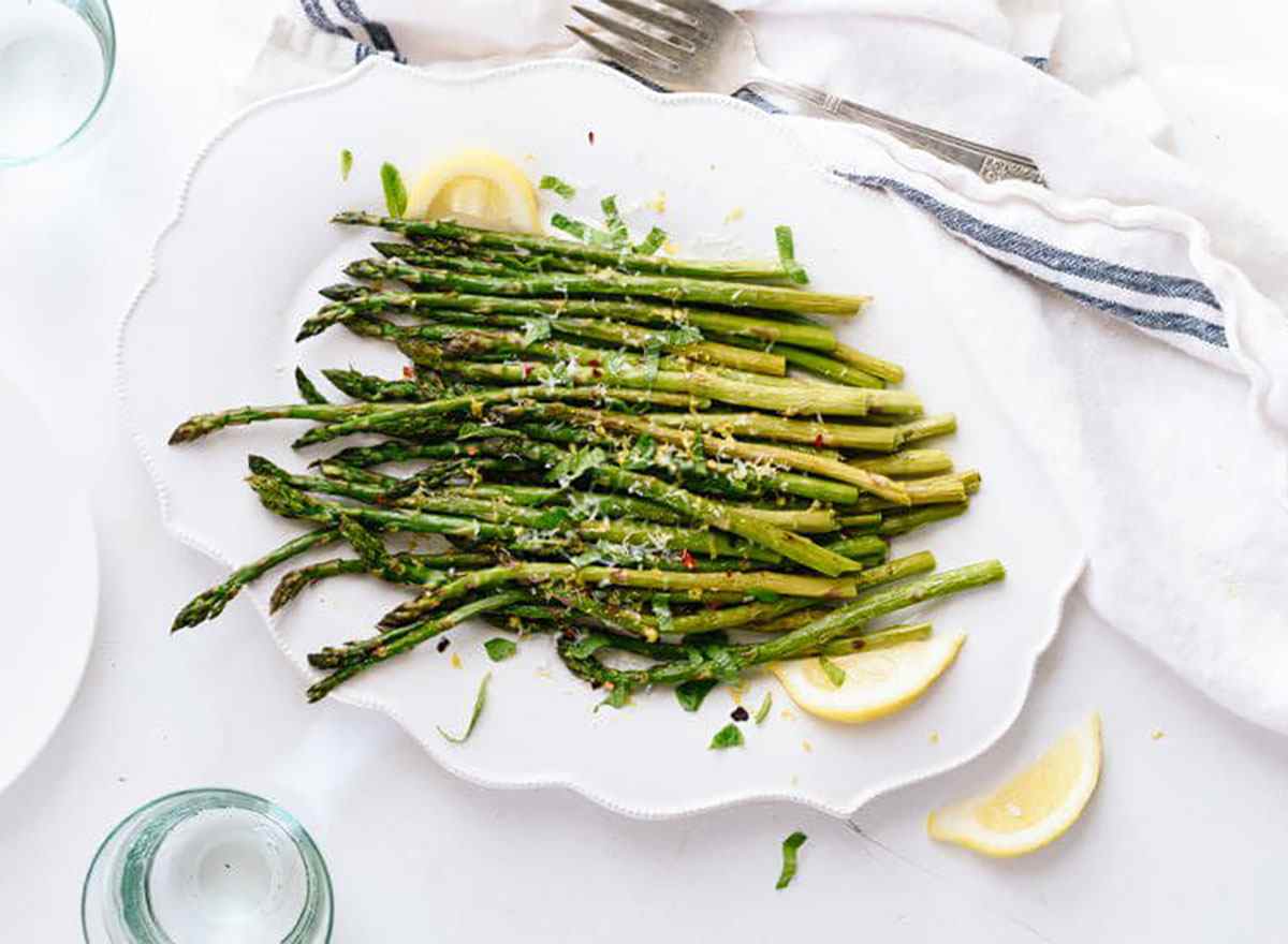 roasted asparagus on serving plate with lemon wedges