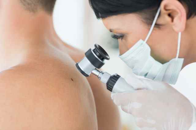 Dermatologe untersucht Maulwurf auf dem Rücken eines männlichen Patienten in der Klinik