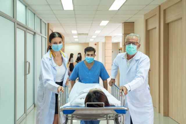 Arzt und Krankenschwester bringen verletzte Patienten von einem Unfall auf einer Bahre in den Not-OP-Saal.