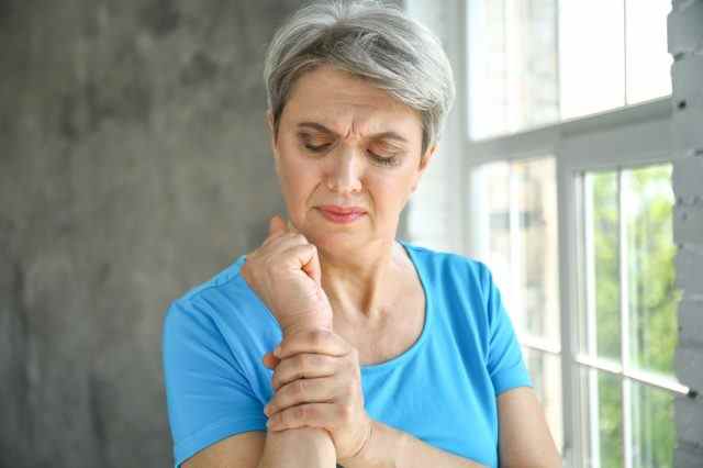 Reife Frau, die zu Hause unter Schmerzen im Handgelenk leidet