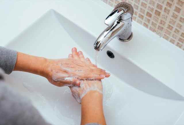Frau wäscht sich zu Hause die Hände mit Wasser und Seife