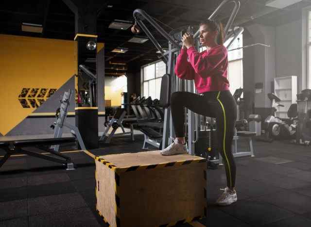 Frau, die im Fitnessstudio Step-up-Übungen macht, um schwache Knie zu stärken
