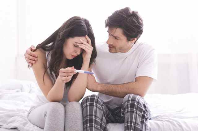 Mann tröstet seine depressive Frau mit negativem Schwangerschaftstest