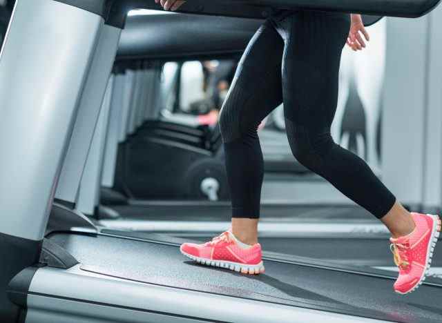 Nahaufnahme einer Frau, die auf der Laufbandneigung läuft, um den Bauchfettabbau im Fitnessstudio während des Laufbandtrainings zu beschleunigen