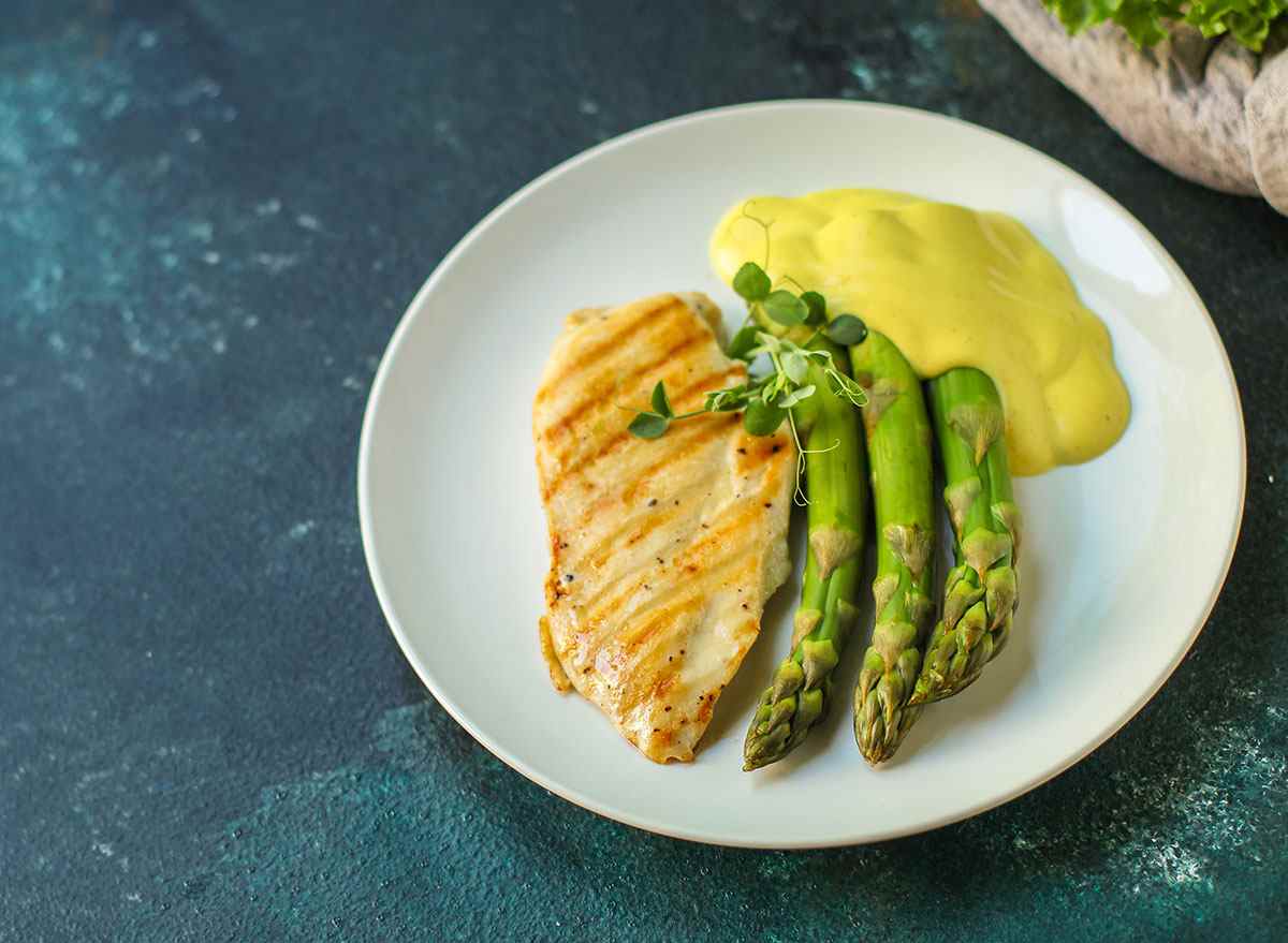 chicken hollandaise with asparagus on white plate
