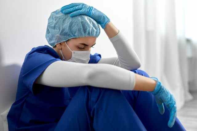 traurige junge ärztin oder krankenschwester mit gesichtsschutzmaske zum schutz