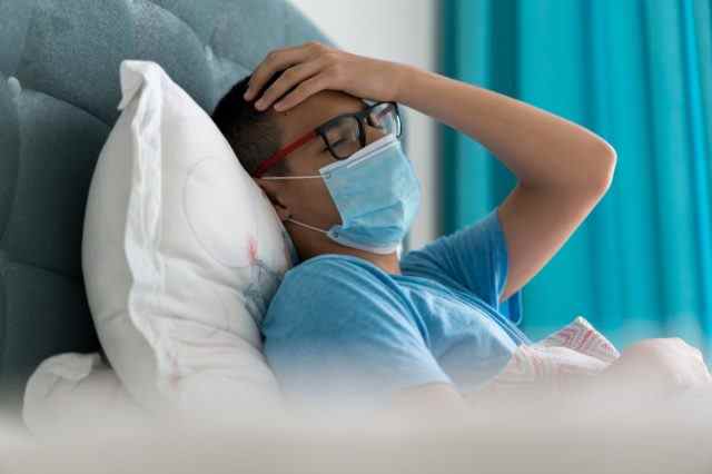 Teenager krank im Bett mit Covid-19-Symptomen
