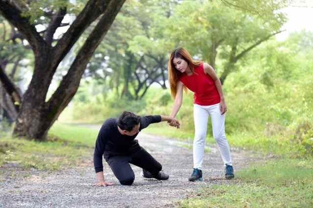 Frau hilft einem verletzten Mann auf der Laufbahn im Garten