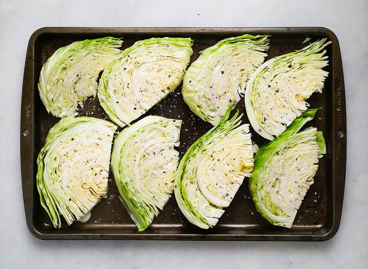 cabbage wedges seasoned with salt and pepper on a baking sheet