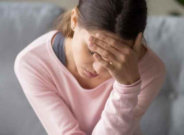 Frau, die zu Hause mit starken Kopfschmerzen oder Migräne zu tun hat