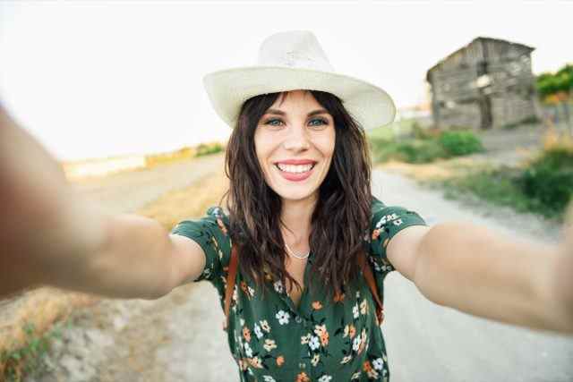 Wanderer junge Frau, trägt ein geblümtes Hemd und macht ein Selfie-Foto im Freien