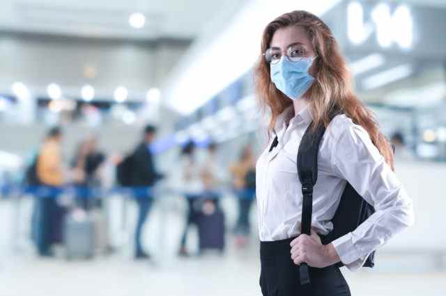 Virusmaske Frau reist mit Gesichtsschutz zur Vorbeugung gegen Coronavirus am Flughafen.