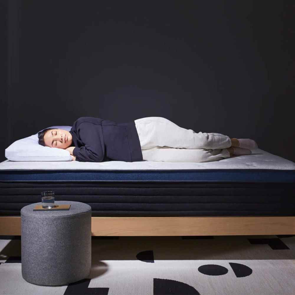 Frau schläft auf einer dunkelblauen Matratze