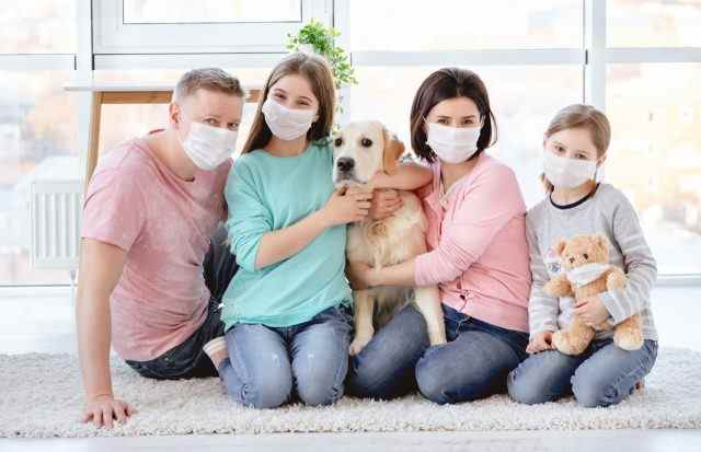 Schöne Familie in medizinischen Masken gegen Coronavirus zu Hause