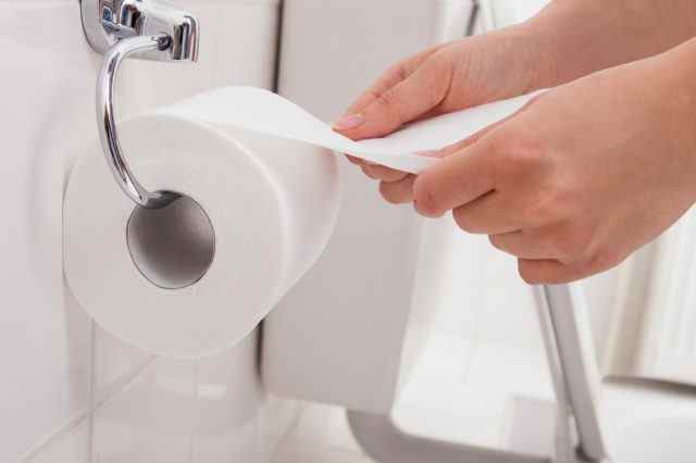 Die Hand der Person, die Toilettenpapier verwendet