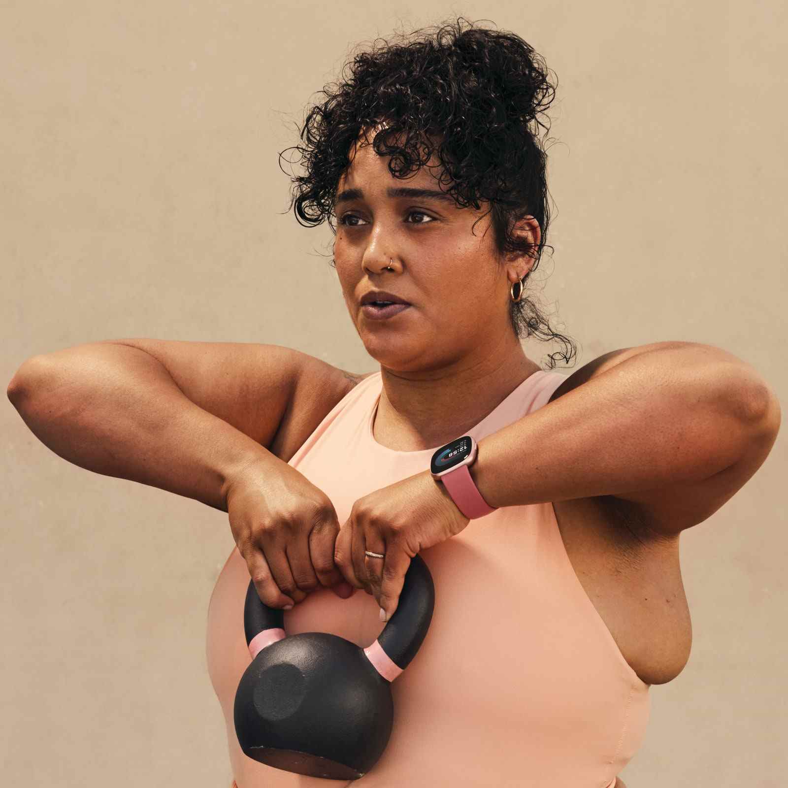 Frauen mit Fitbit Versa 4 Fitness-Tracker und Kettlebell in der Hand