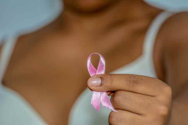 Die Hand einer afrikanischen Frau, die eine rosa Schleife gegen Brustkrebs hält