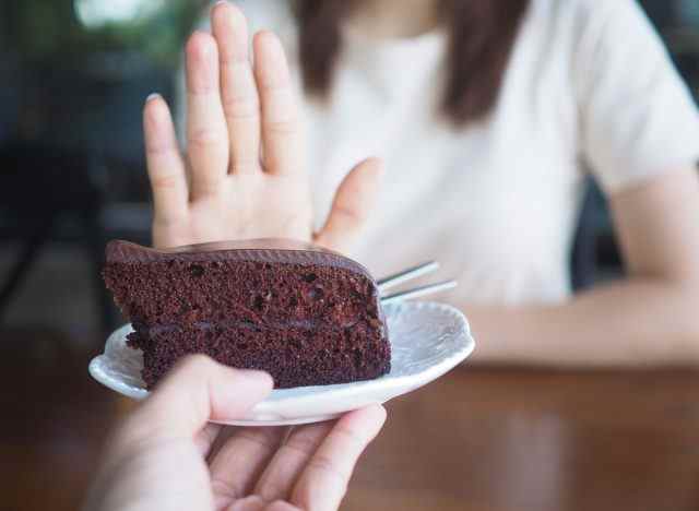 Frau sagt Nein zum Dessert mit Schokoladenkuchen