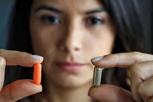 Junge hispanische Frau, die zwischen Antibiotika oder alternativer Medizin wählt.