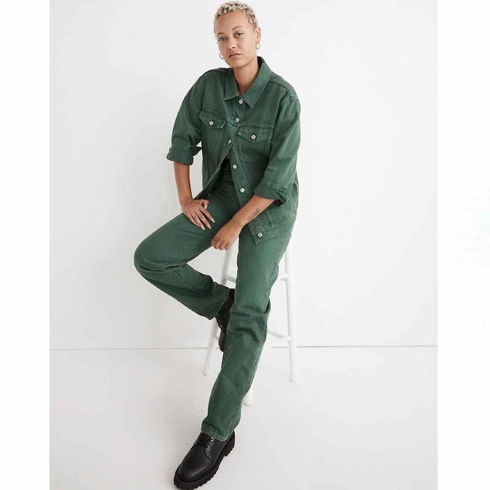Grüne Madewell The Oversized Trucker Jacket auf einem Modell, das eine passende Hose trägt und auf einem Hocker sitzt