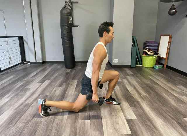 Trainer demonstriert Kurzhantel-Split-Kniebeugen, um Ihren Stoffwechsel nach 40 anzukurbeln