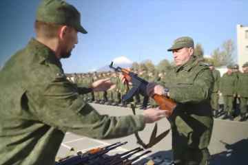 Zivilisten, die gezwungen wurden, sich dem russischen Blutbad anzuschließen, überreichten rostige Kalaschnikows