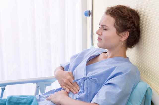 Patientin mit Periodenschmerzen im Schlafzimmer des Krankenhauses