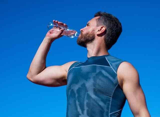 sportlicher Mann trinkt Wasser im Freien an einem sonnigen Sommertag
