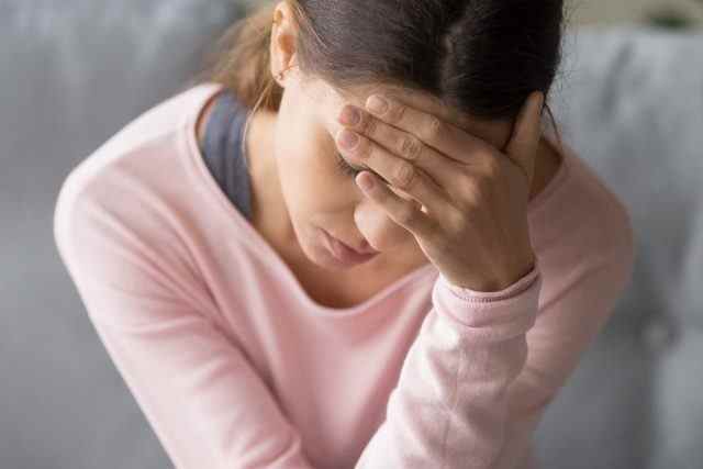 Frau, die zu Hause mit starken Kopfschmerzen oder Migräne zu tun hat