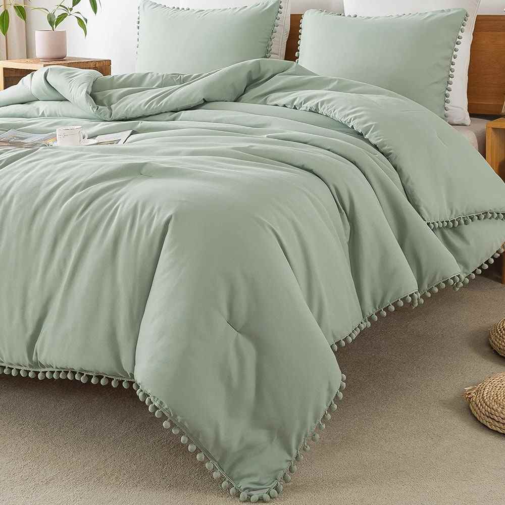 Litanika Sage Green Pom Pom Fringe Bettdecke auf dem Bett