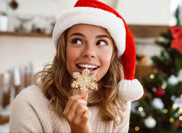 Frau in Weihnachtsmütze, die Lebkuchen-Weihnachtsplätzchen isst