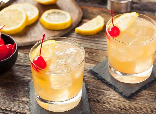 Whiskey Sour Cocktails im Glas mit Kirsch-Zitronen-Garnitur