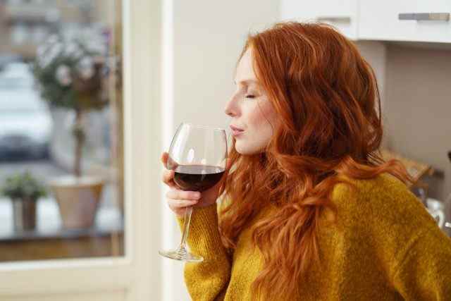 Frau, die zu Hause Weinalkohol trinkt