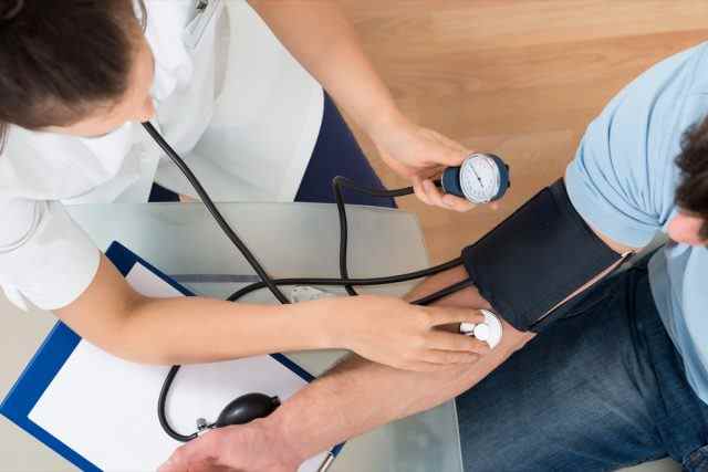 Arzt überprüft den Blutdruck eines männlichen Patienten