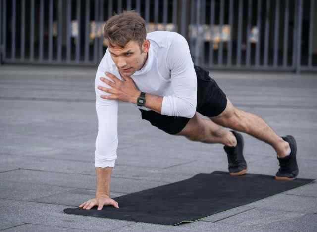 Mann demonstriert Planken-Schulterklopf-Übungen, um Muskelmasse in Ihren Armen wiederzugewinnen