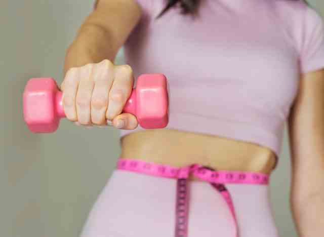 frau, die rosa hantel-gewichtsverlustkonzept hält