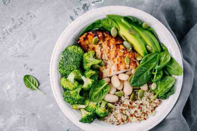 Gesunde Quinoa Lunch Bowl mit Hühnchen als Protein Avocado als Fett und Gemüse Brokkoli und Spinat und Bohnen