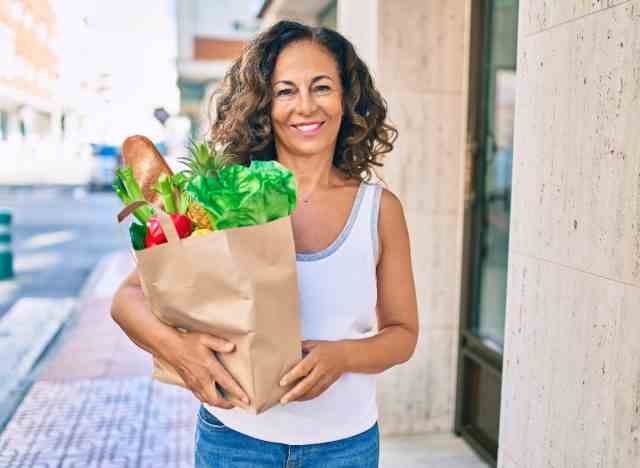 Reife Frau, die Lebensmittel hält und Gewohnheiten demonstriert, um die Muskelmasse nach 50 zu erhalten
