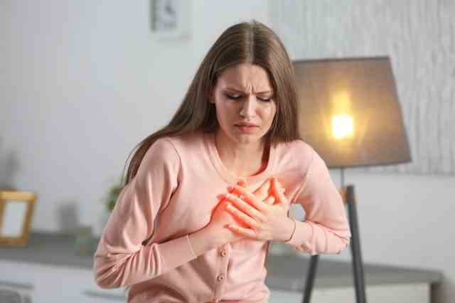Frau, die unter Brustschmerzen im Innenbereich leidet