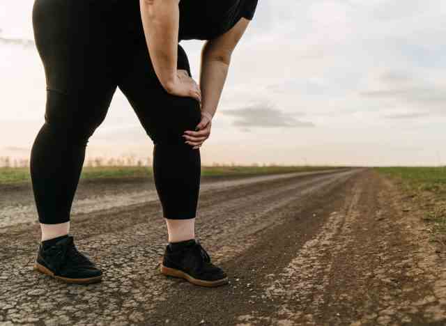 Übergewichtige Frau mit Knieschmerzen beim Gehen, Konzept der Zeichen, die Sie brauchen, um Gewicht zu verlieren