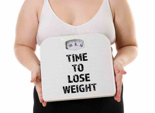 frau, die waagenzeichen hält, die sie benötigen, um gewichtskonzept zu verlieren