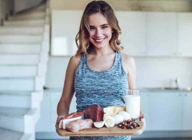 frau hält tablett mit proteinreichen lebensmitteln in der küche, um nach gewichtsverlust muskelmasse aufzubauen