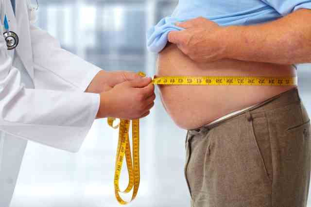 Arzt misst fettleibigen Mann Taille Körperfett.  Fettleibigkeit und Gewichtsverlust