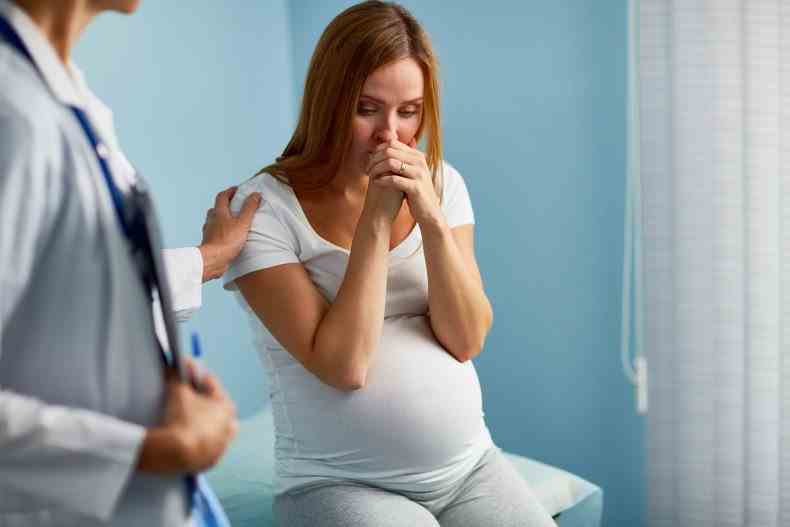 Schwangere Frau schaut verärgert in die Arztpraxis.
