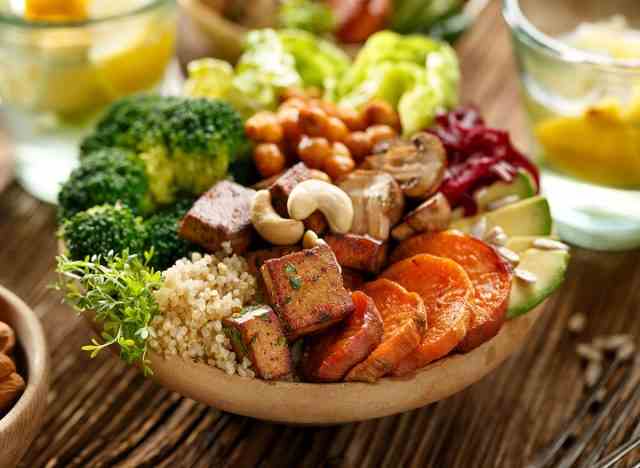 Buddha Bowl mit pflanzlichen Lebensmitteln wie Brokkoli, Nüssen, Tofu, Karotten, Avocado und vielem mehr