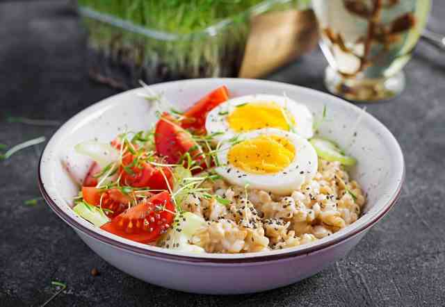Frühstücks-Haferflocken mit gekochtem Ei, Kirschtomaten, Sellerie und Microgreens.  Gesundes ausgewogenes Essen.